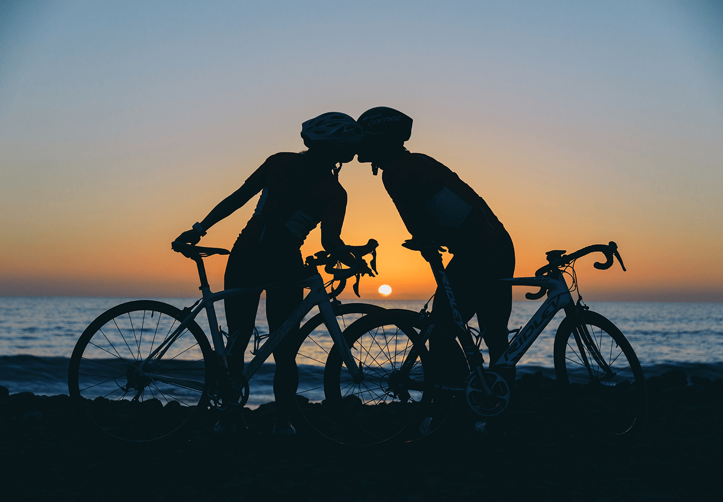 Cyclistes qui s'embrassent devant un coucher de soleil