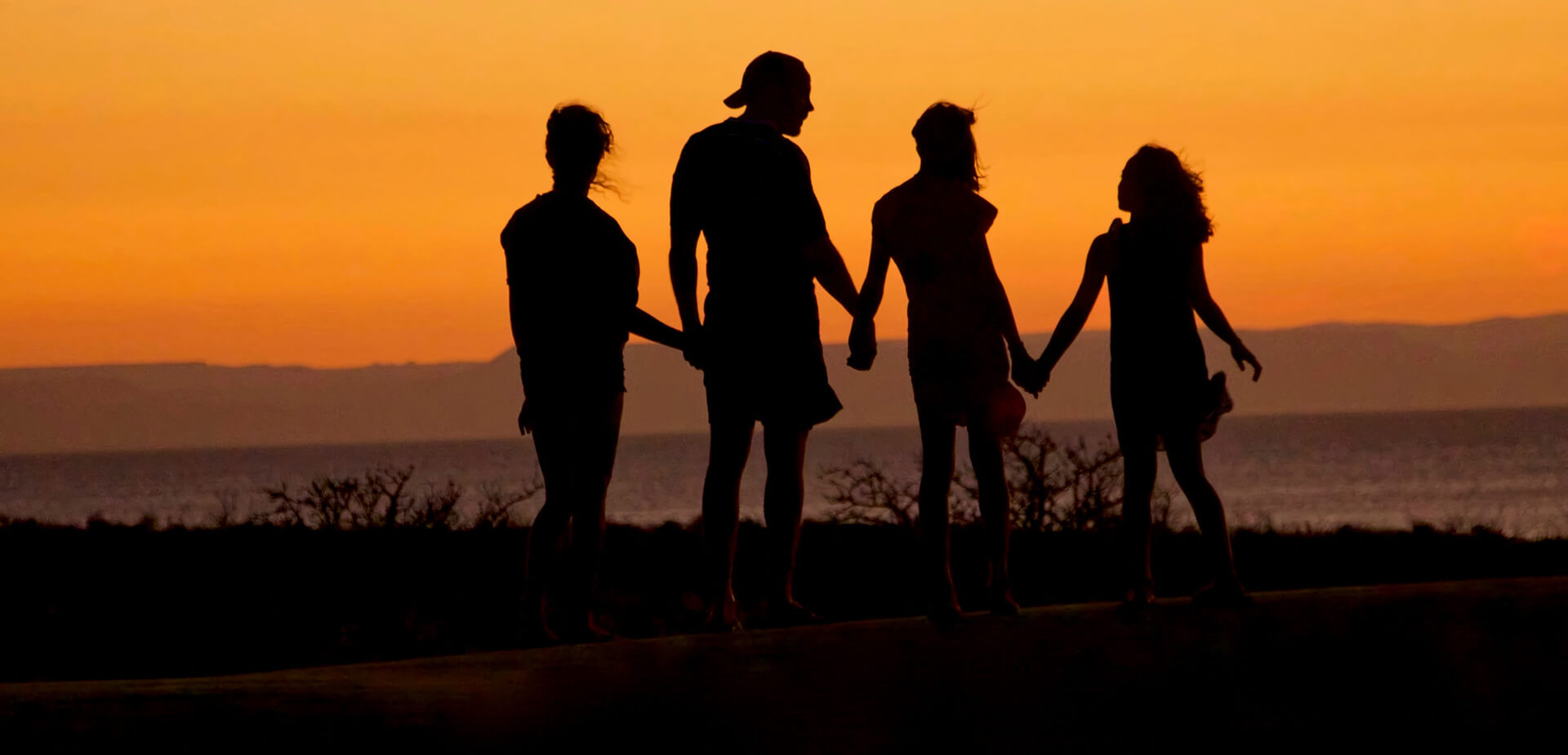 Famille devant un coucher de soleil main dans la main