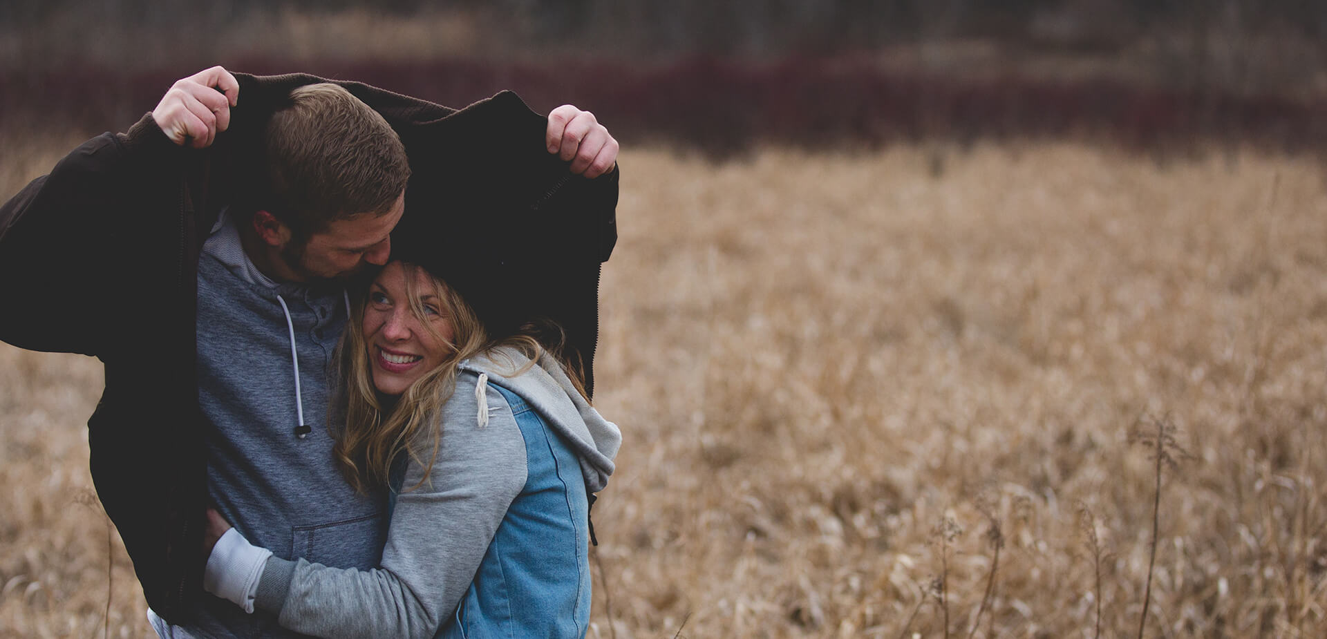 Couple se mettant à l'abris d'une pluie dans un champ