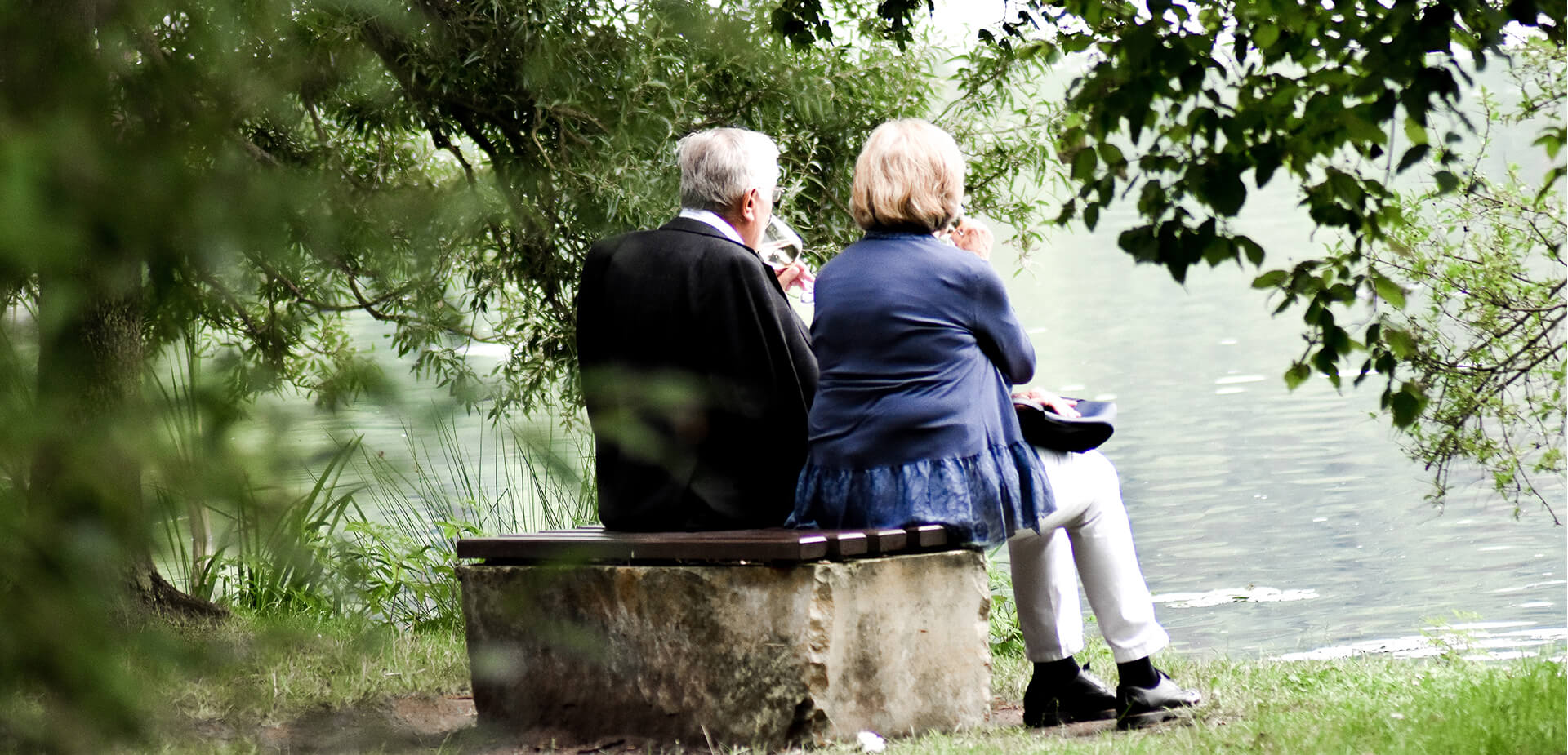 Couple savourant une coupe de vin sur le bord d'un étang
