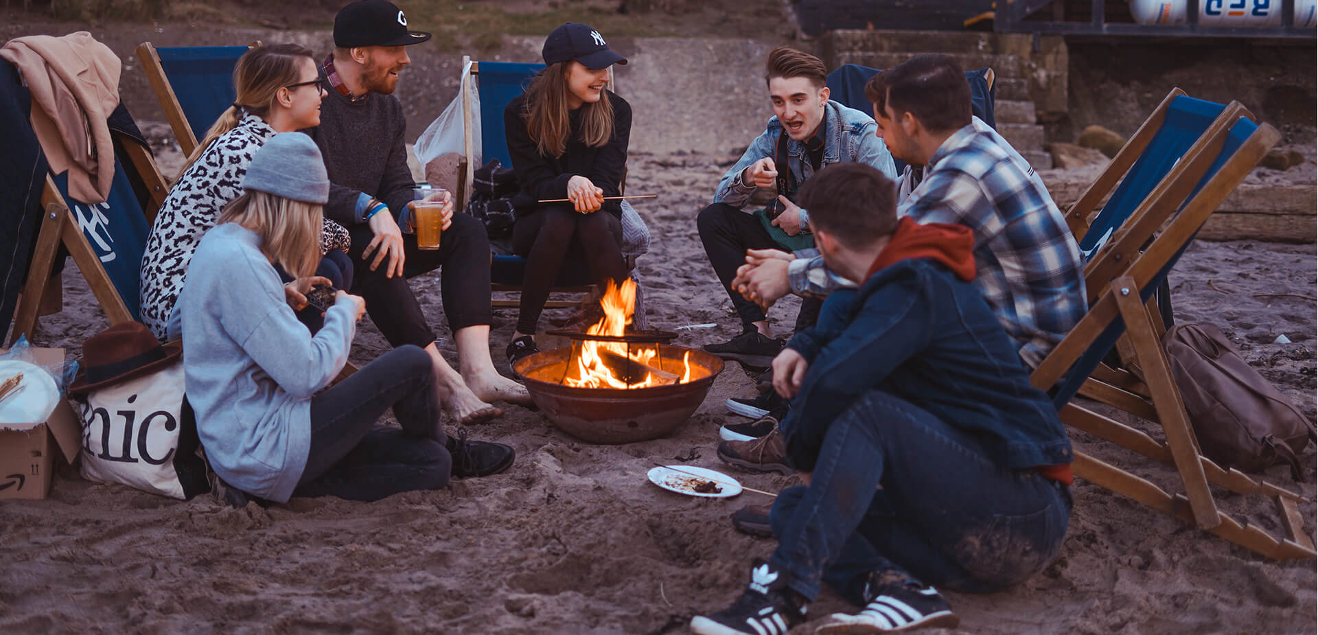 Jeunes amis assis autour d'un feu sur une plage